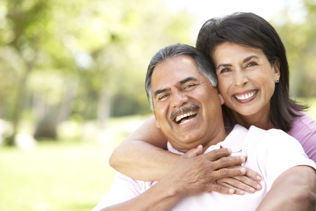 Two adults laughing together outdoors.